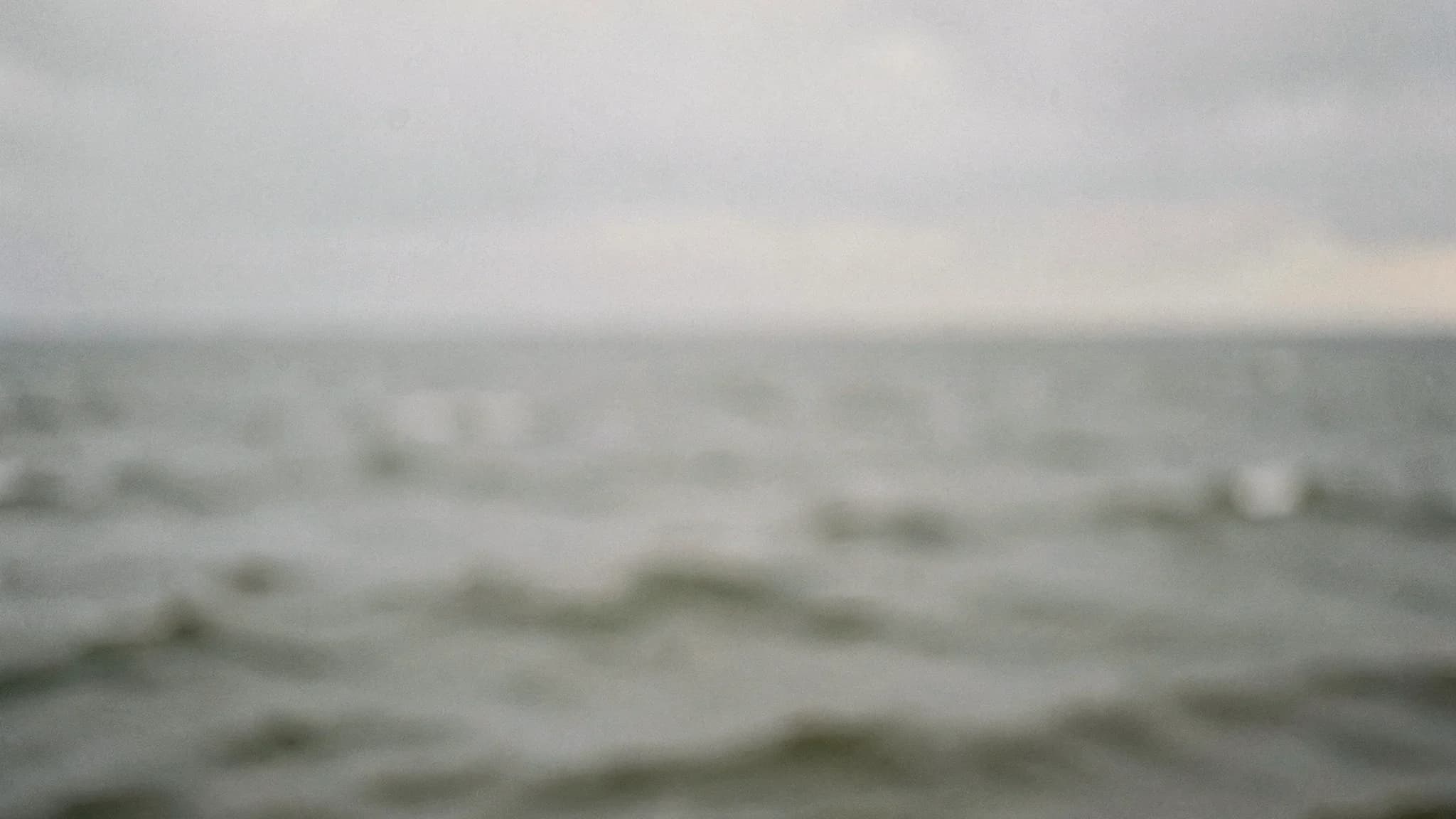 Onscherpe deinende grijze zee zonder zichtbare horizon
