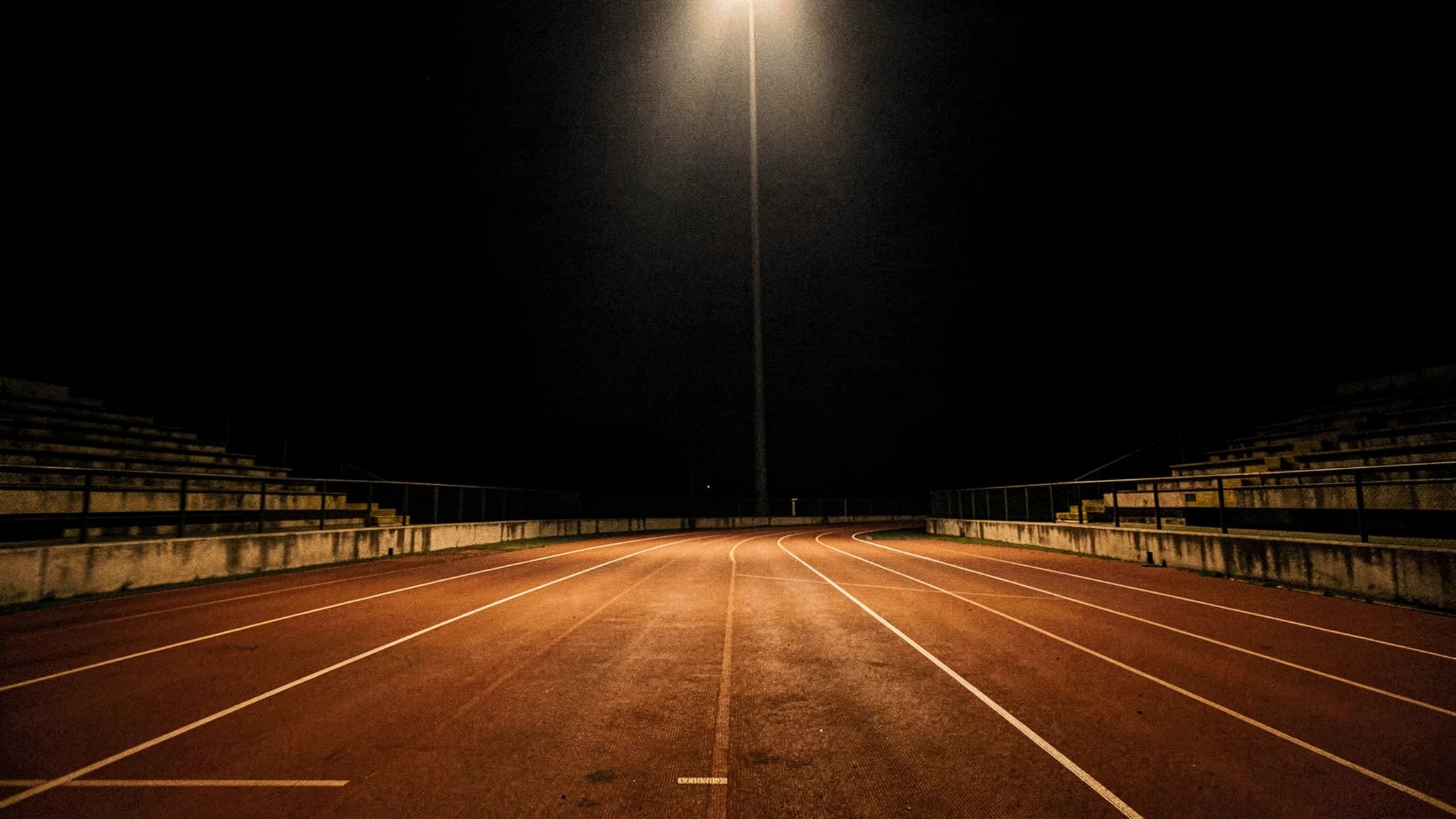 Lege atletiekbaan bij nacht onder een enkele schijnwerper