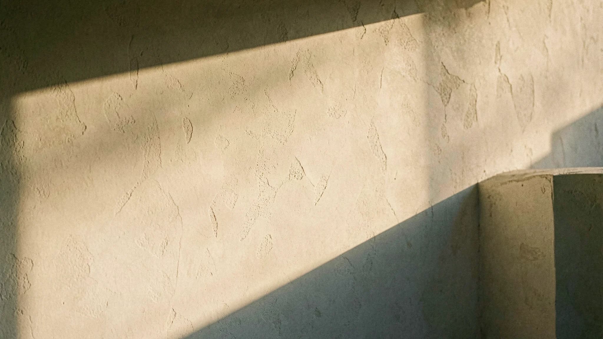 Warme gekalkte muur met zacht lichtverloop en schaduw
