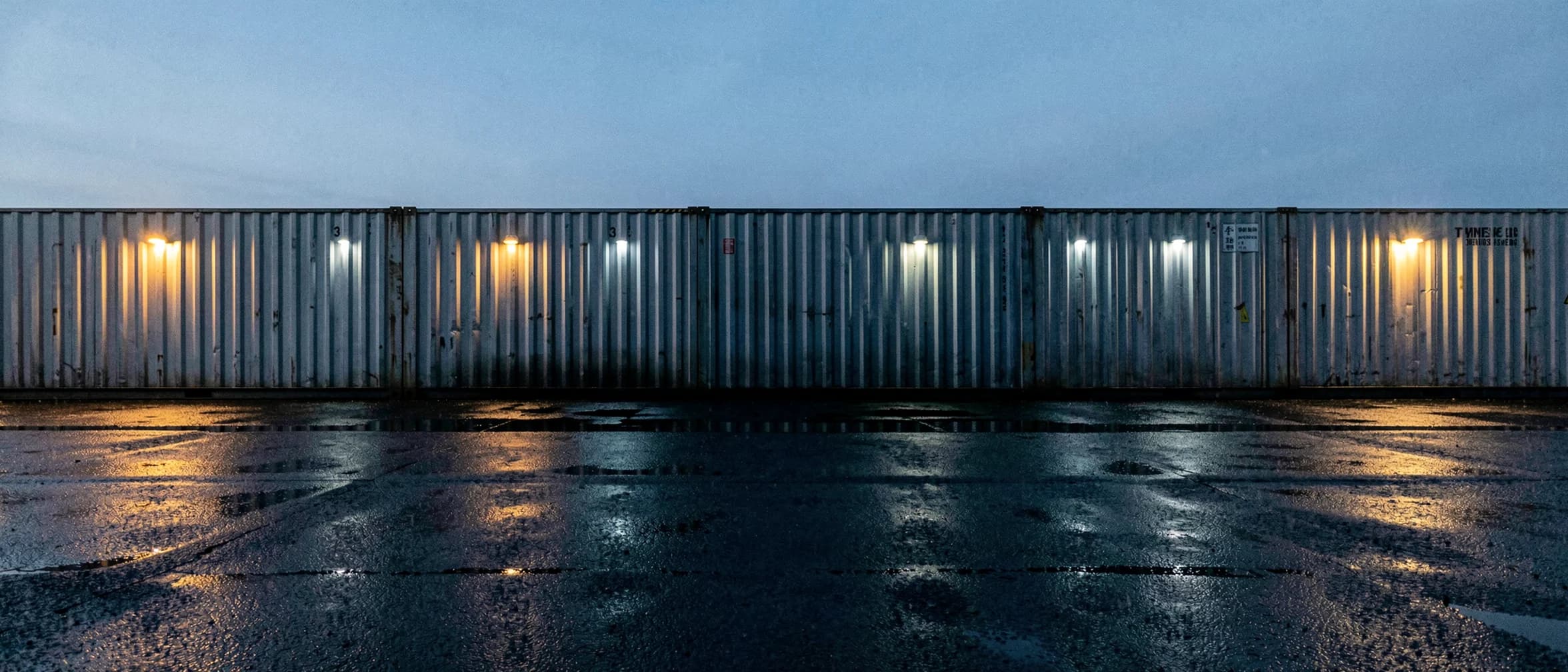 Rij zeecontainers over de volle breedte met strijklicht