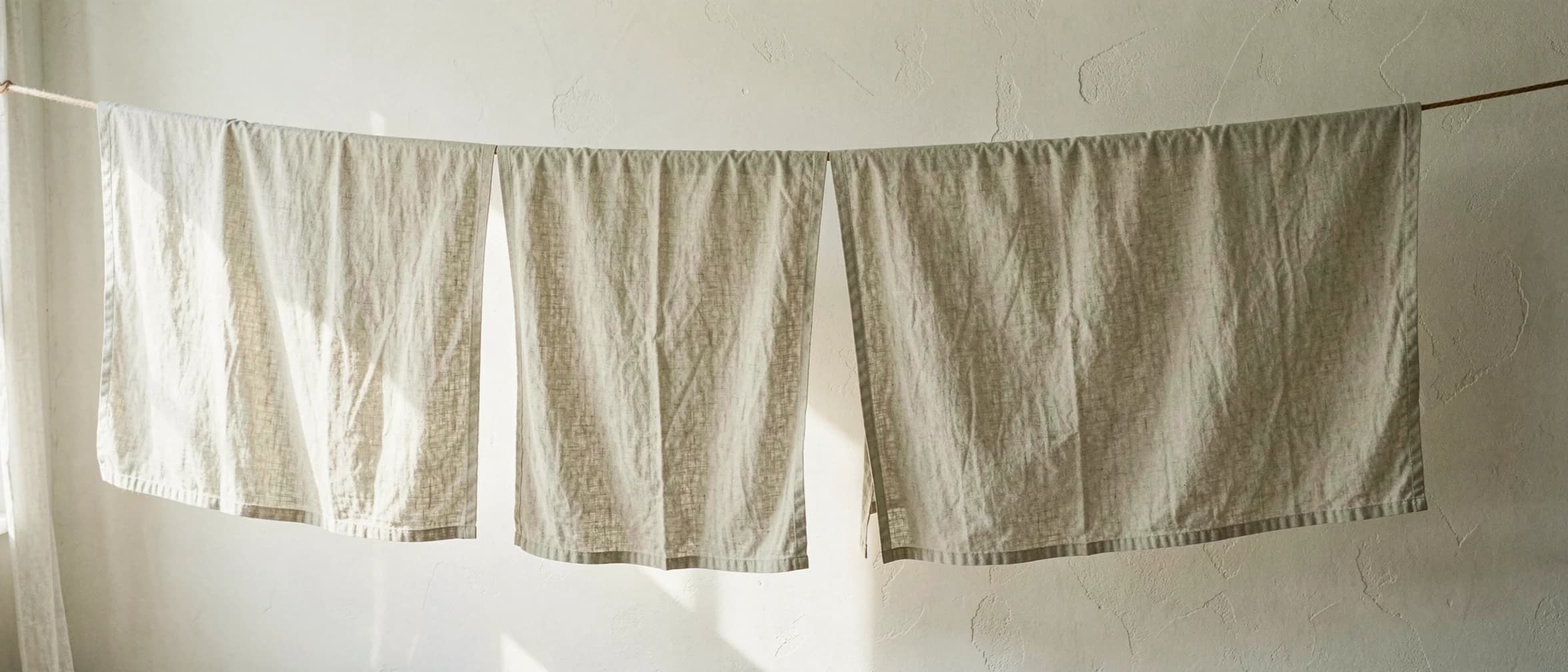 Gewassen linnen lakens aan een drooglijn binnenshuis
