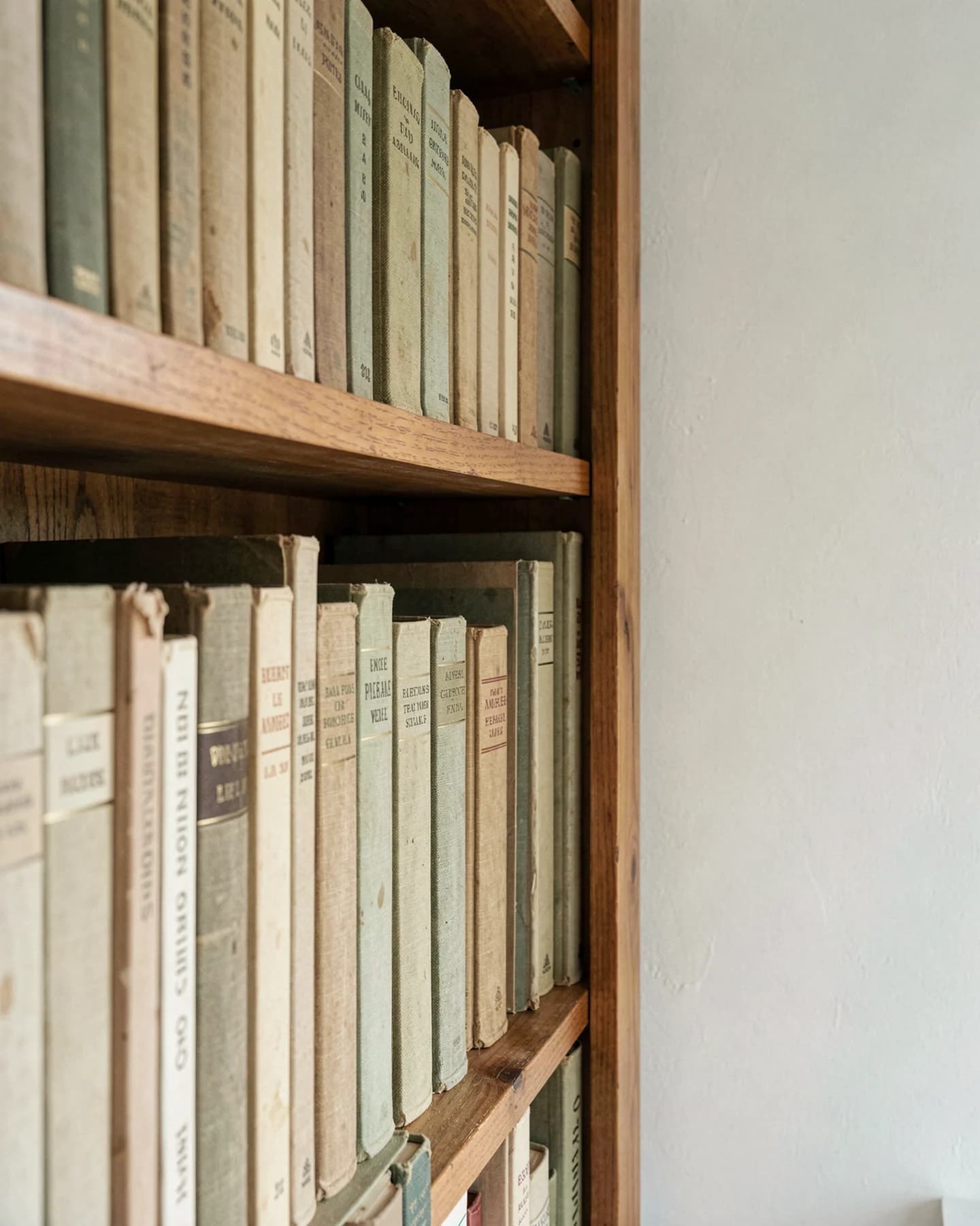 Smalle houten boekenkast met verweerde linnen banden