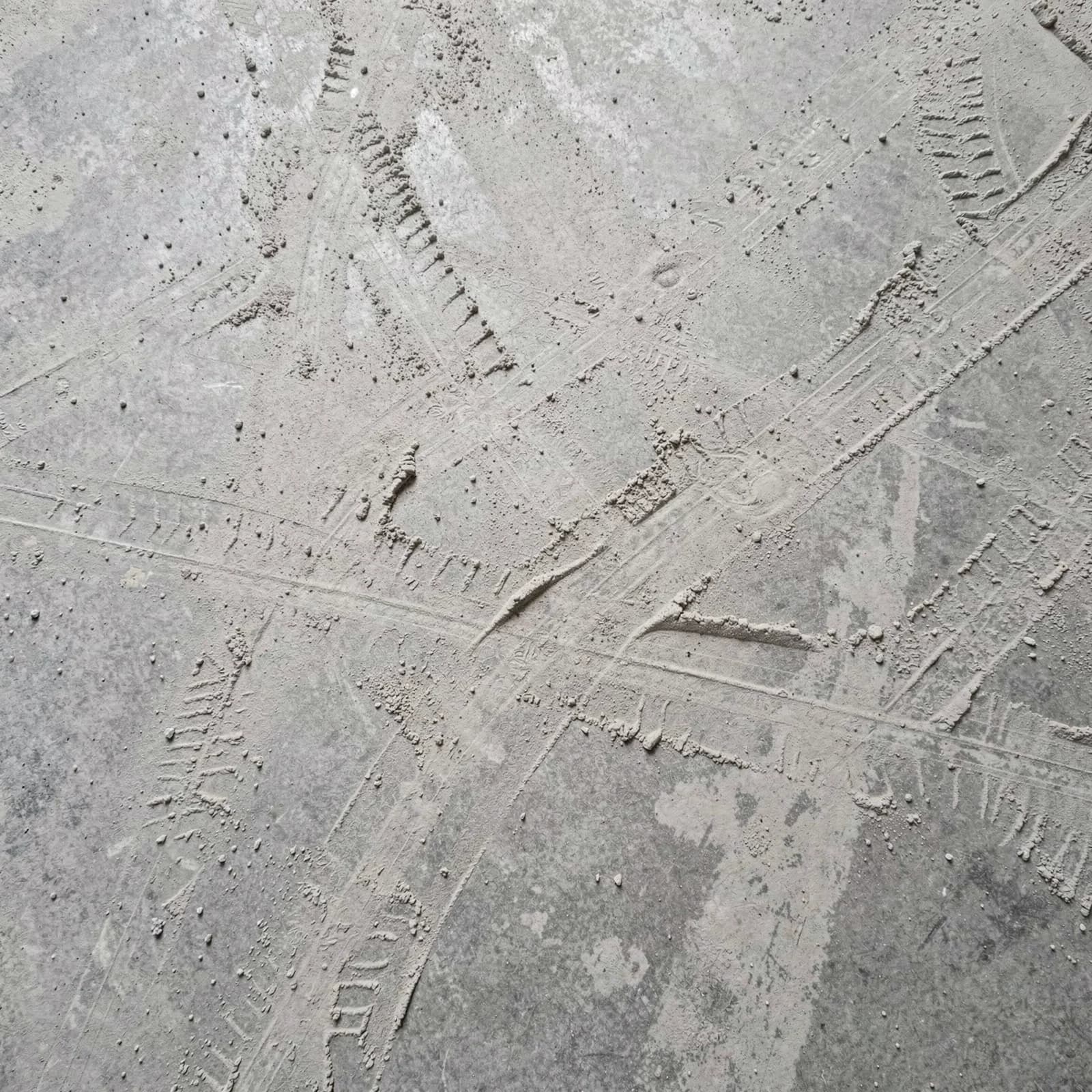 Geveegde betonvloer met fijn bouwstof en sleepsporen