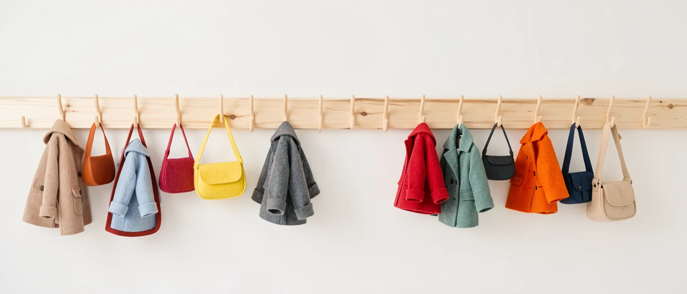 Lage kapstok met kinderjasjes aan een berkenhouten lat