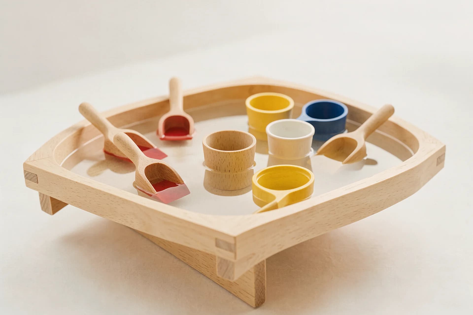 Ondiepe watertafel met drijvende houten bakjes en schepjes